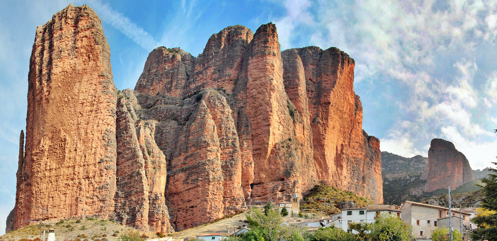 Paisaje de Mallos de Riglos, Huesca. Formaciones rocosas imponentes y pueblo pintoresco. Turismo rural y aventura en Aragón.