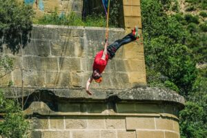 Hombre haciendo puenting en puente de piedra. Aventura y deportes extremos en la naturaleza.|
