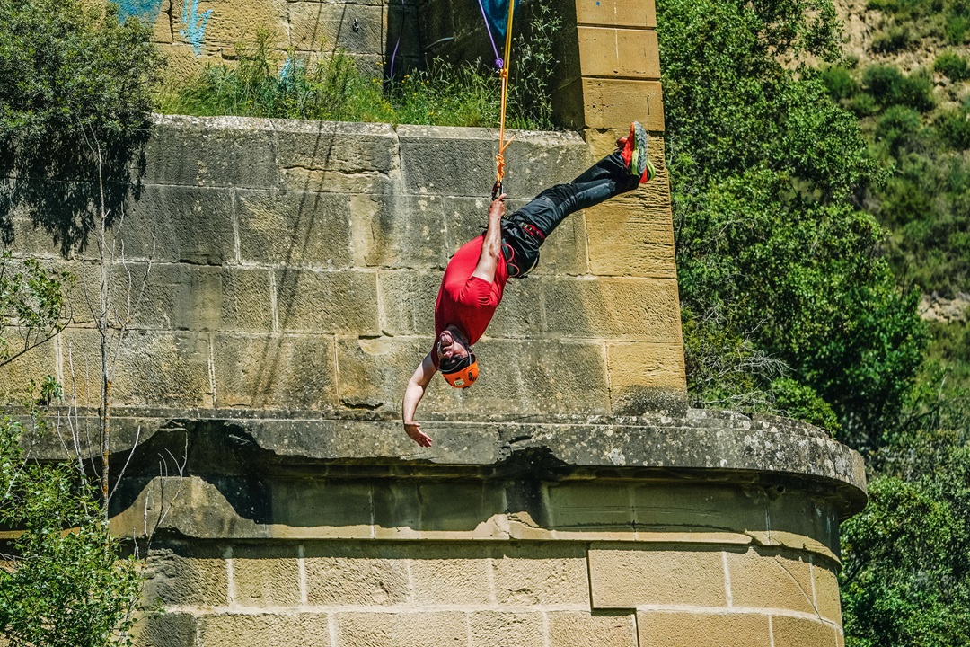 Hombre haciendo puenting en puente de piedra. Aventura y deportes extremos en la naturaleza.|